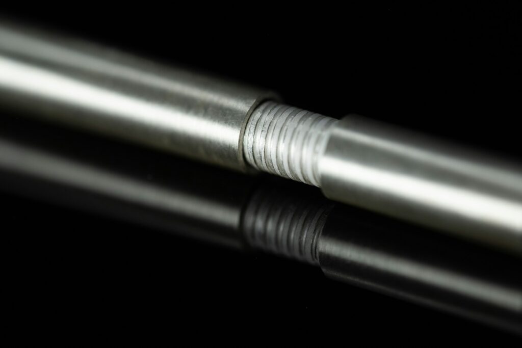 Threaded metal rod with a reflective finish lying on a black surface