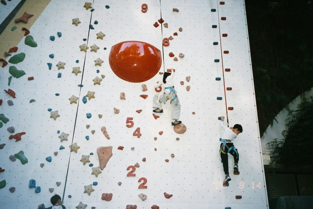 Children climbing a colourful indoor rock wall at a climbing session