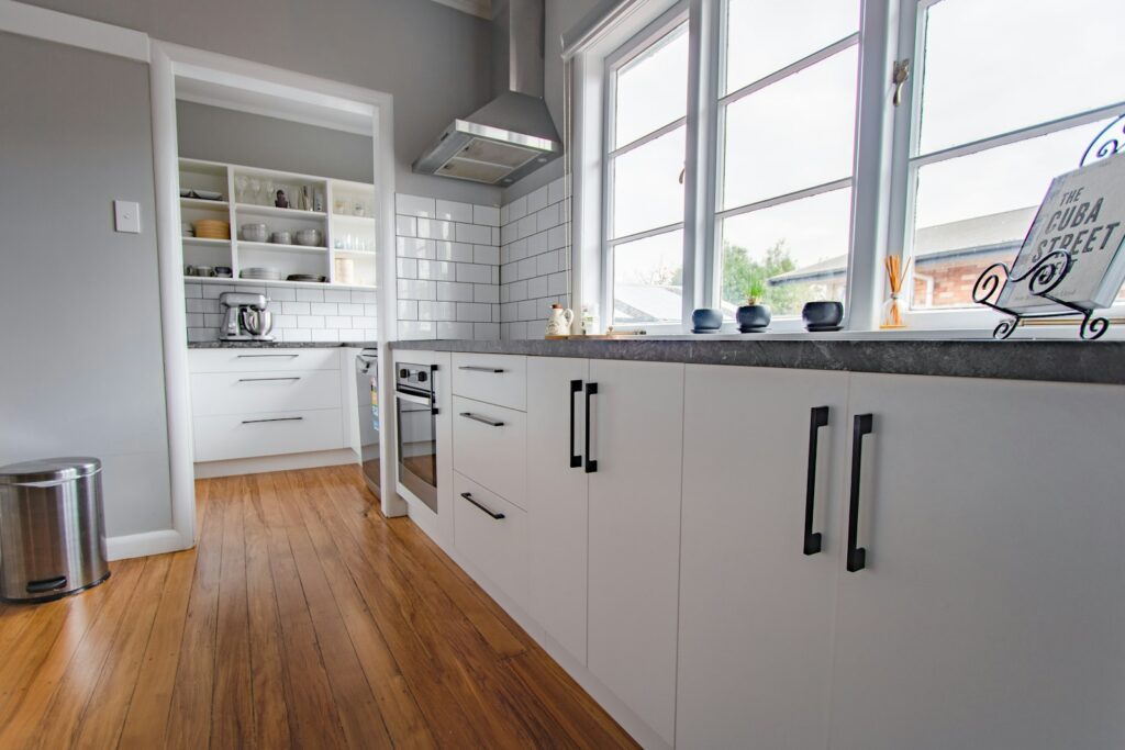 White wooden kitchen cabinets with black handles in a simple, bright kitchen