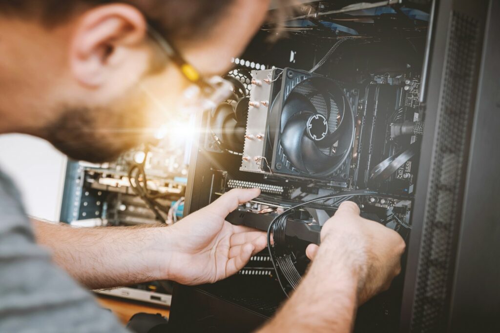 Person fitting a graphics card inside a computer case with a cooling fan visible