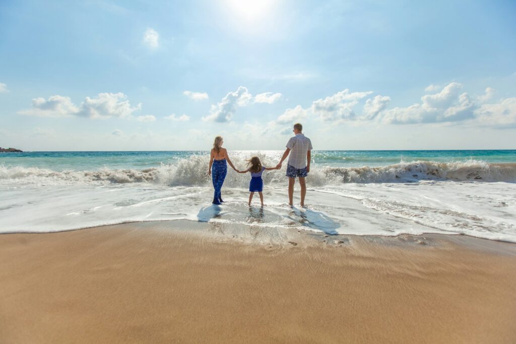 Man, woman and child holding hands as they walk along the seashore